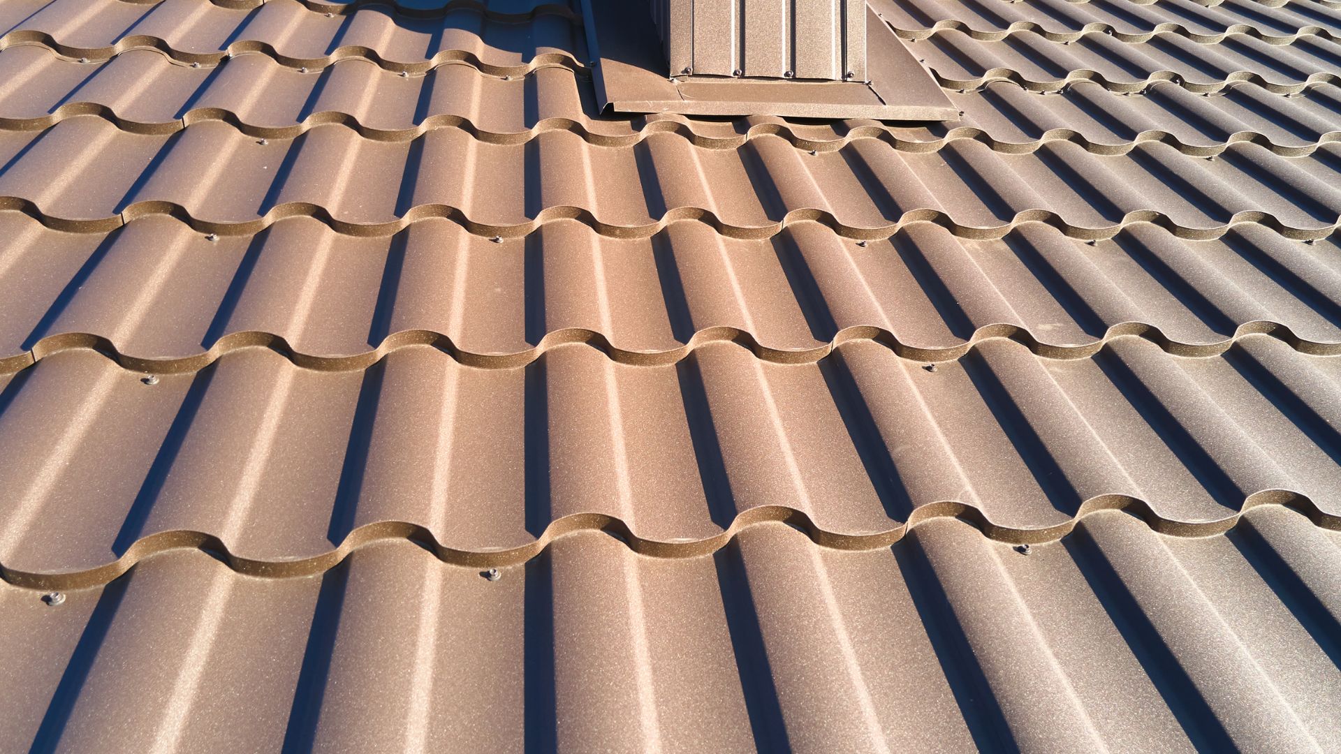 A close up of a metal roof with a bench in the background