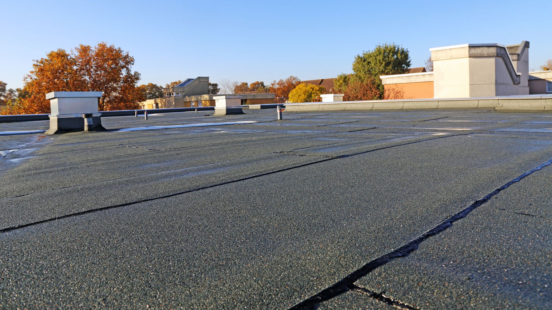The flat roof of a commercial building with snow on the ground